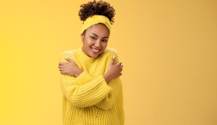 A young black woman in a yellow sweater posing on a yellow background.