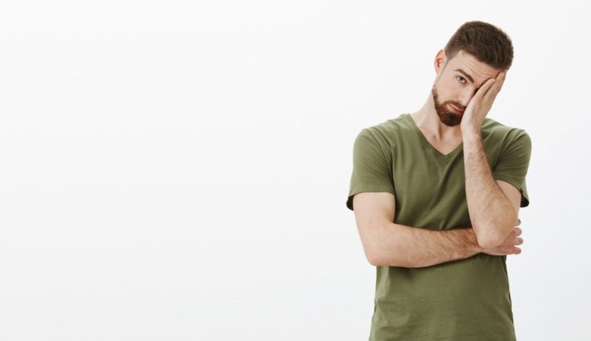 A man in a green t - shirt with his hand on his head.