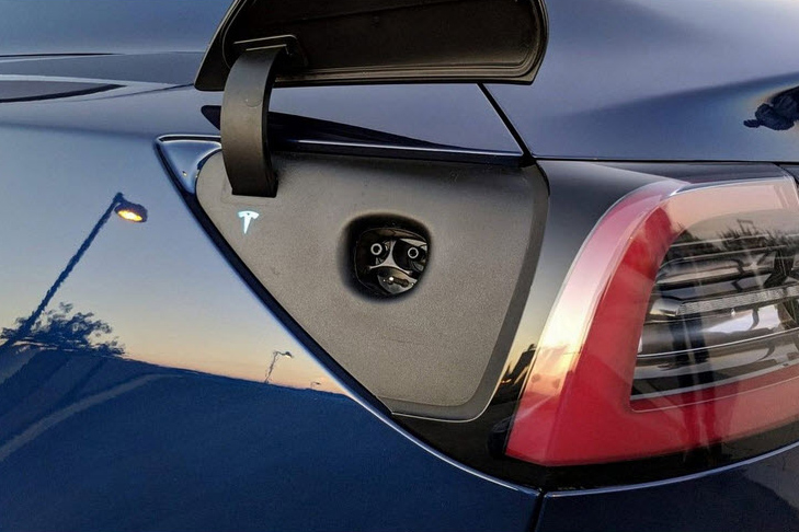 A blue tesla model s with a charging port.