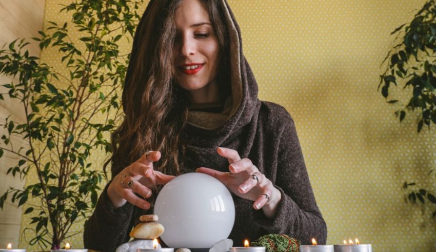 A woman is holding a crystal ball in front of candles.