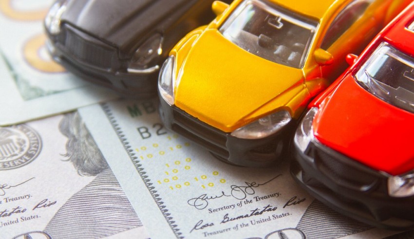 A toy car sits on top of a stack of dollar bills.