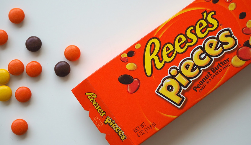 A box of reese's pieces sitting on a table.