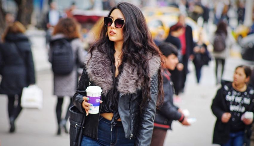 A woman walking down the street holding a cup of coffee.
