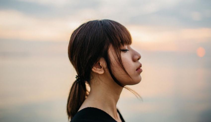 A young woman looking at the ocean at sunset.