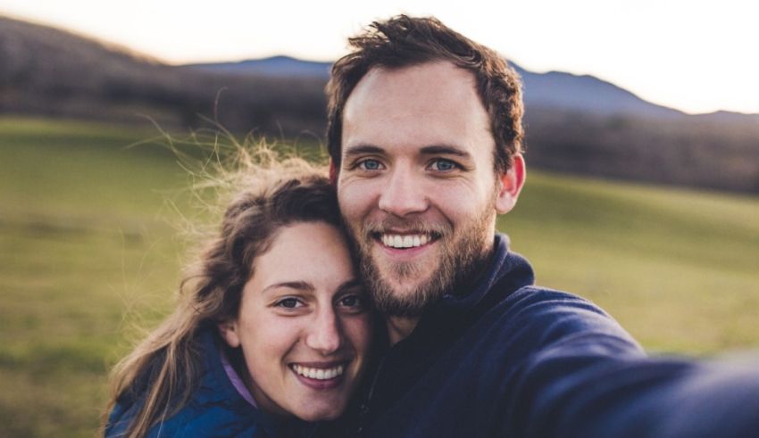 A man and woman taking a selfie in a field.