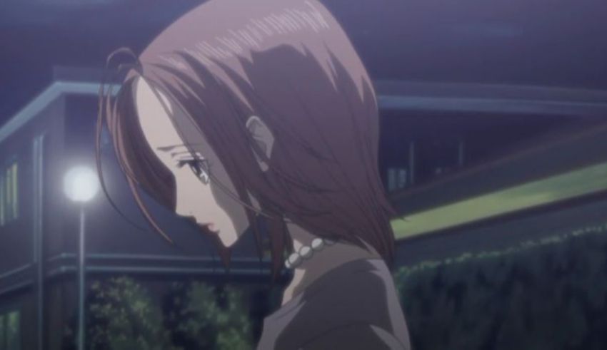 A girl with long brown hair is standing in the street at night.