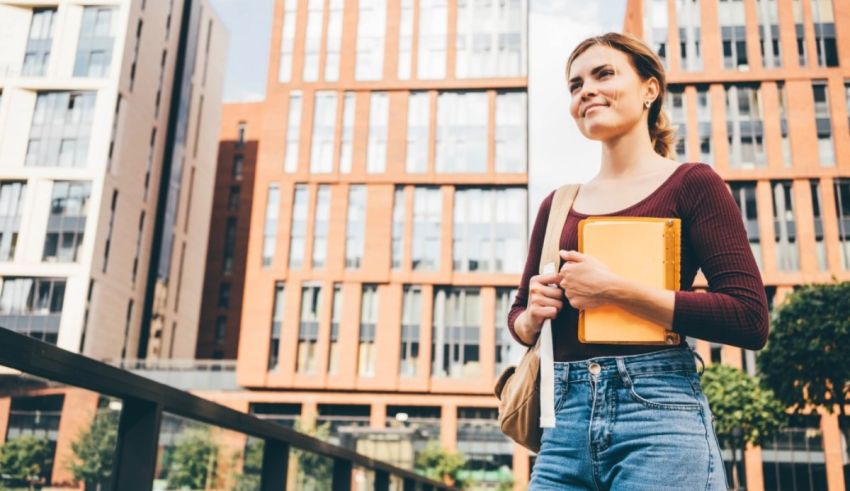 A young woman in jeans and a t-shirt is standing in front of a building.