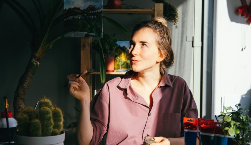 A woman sitting at a table with a cactus in front of her.