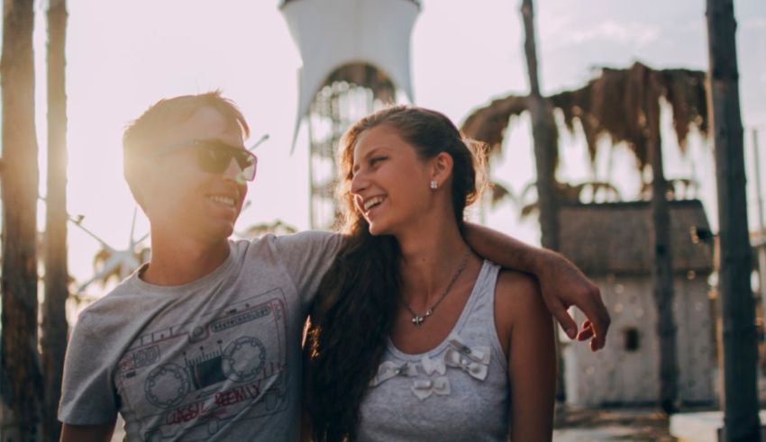 A man and woman are smiling in front of a water tower.