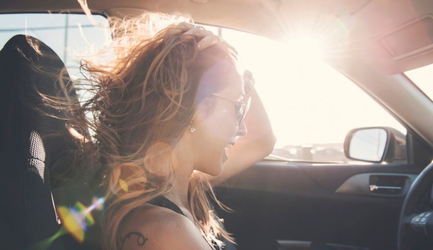 A woman in a car with her hair blowing in the wind.