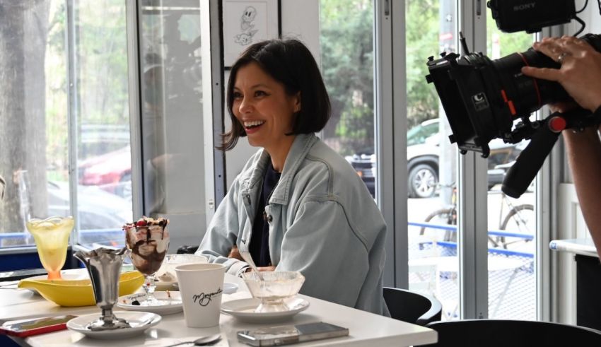 A woman sitting at a table with a camera in front of her.