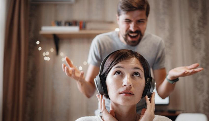 A man is yelling at a woman while wearing headphones.