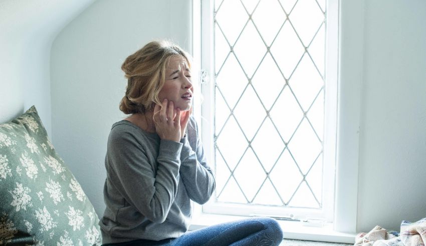 A woman sitting on a bed with her hands on her face.