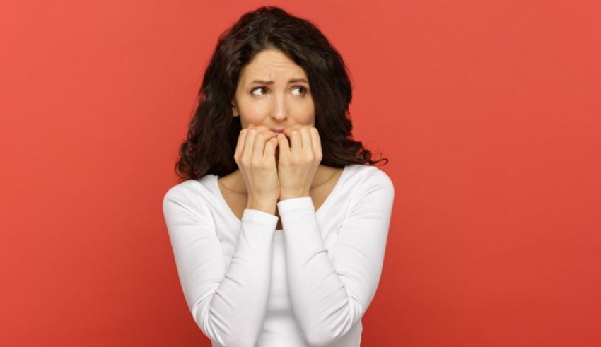 A woman covering her mouth with her hands against a red background.