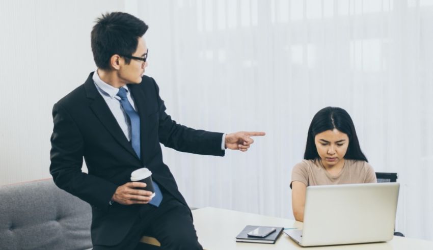 A man in a suit is pointing at a woman in an office.