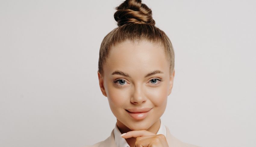 A young woman in a business suit posing with her hand on her chin.