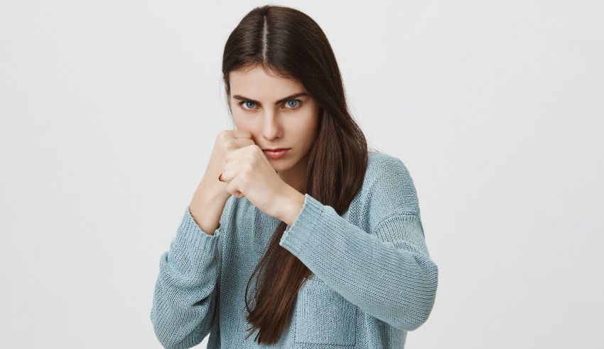 A young woman punching her fist against a white background.