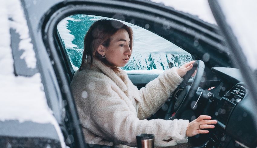 A woman driving her car in the snow.
