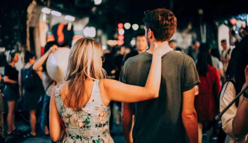 A man and woman are walking down a street at night.