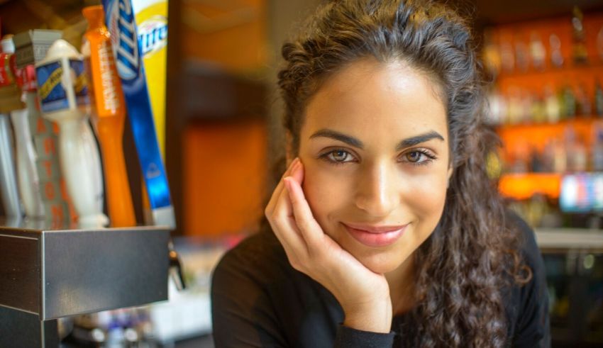 A woman with curly hair is leaning against a bar.