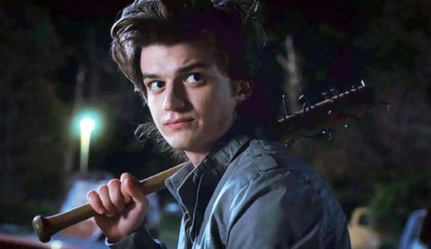 A young man holding a baseball bat at night.