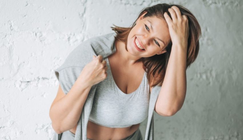 A woman is holding her head up while leaning against a wall.
