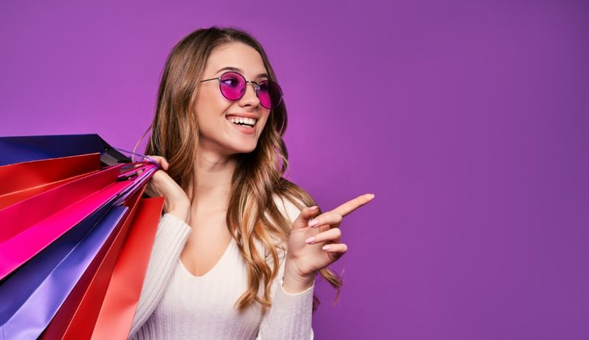 Young woman holding shopping bags on purple background.