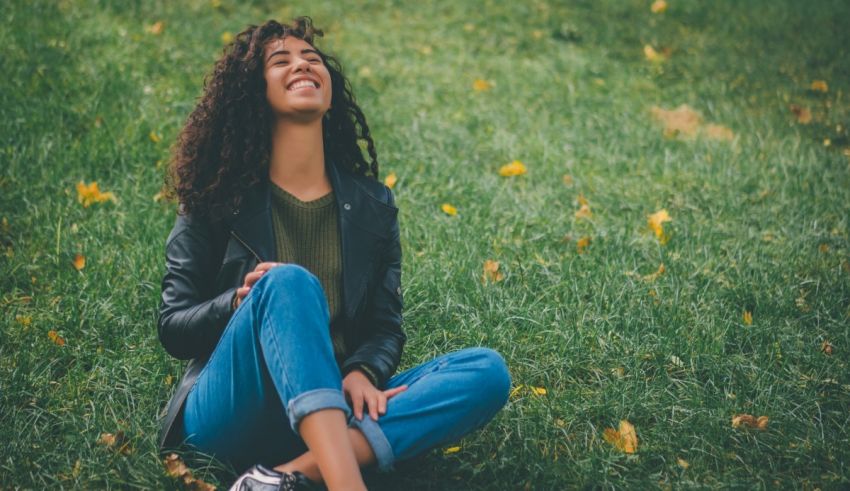 A woman sitting in grass smiling.