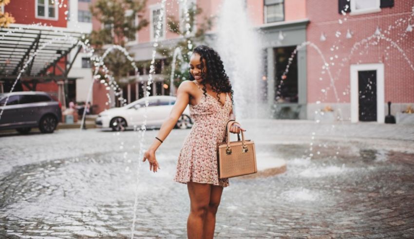 A woman in a pink dress standing in front of a fountain.