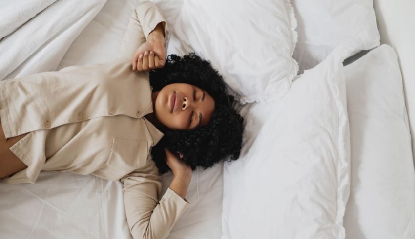 A young woman laying on a white bed.
