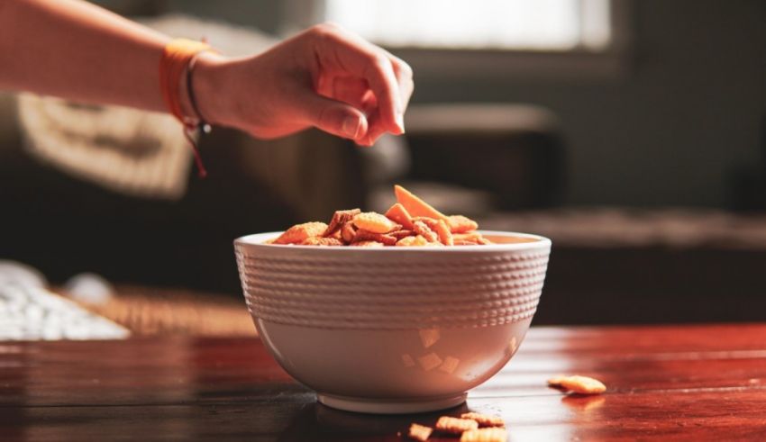A hand reaching into a bowl of crackers.