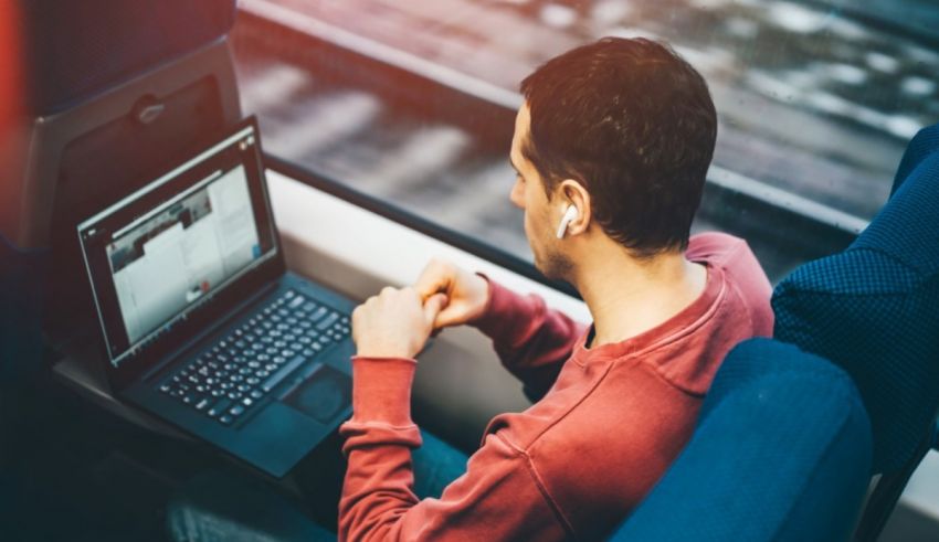 A man sitting in a chair using a laptop.