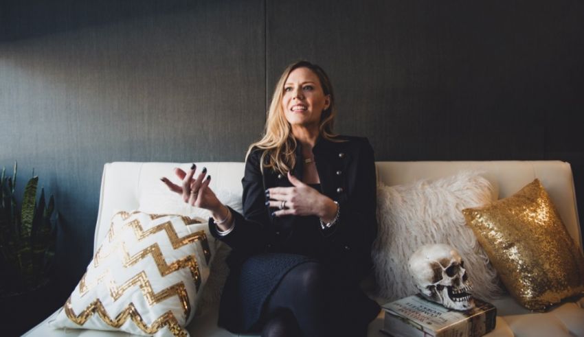 A woman sitting on a couch with gold pillows.