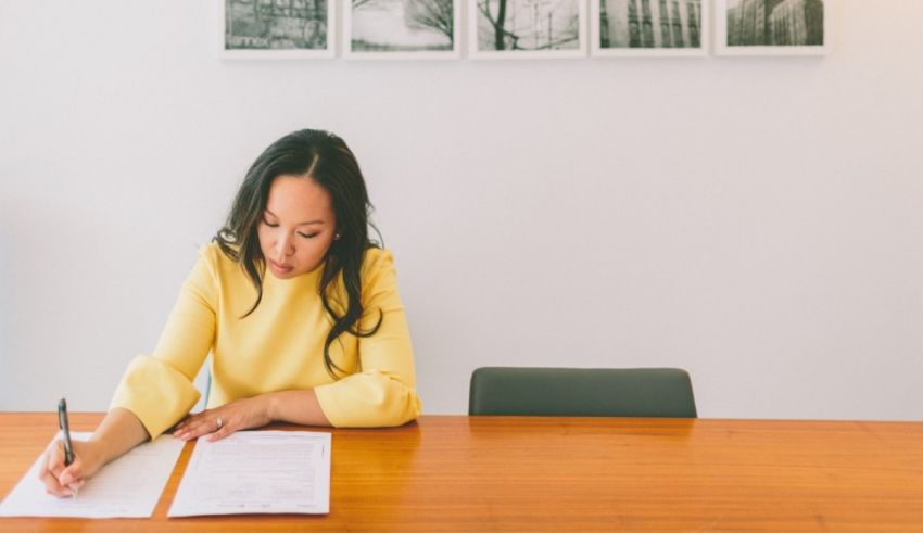 A woman signing a document at a desk.