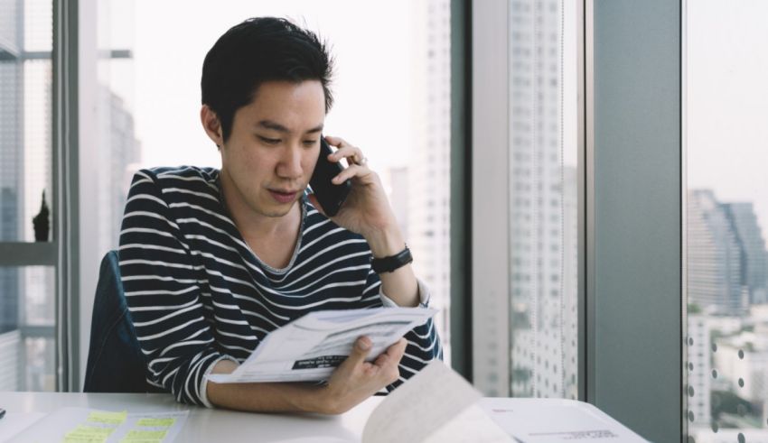 Asian businessman talking on the phone while sitting at a desk.