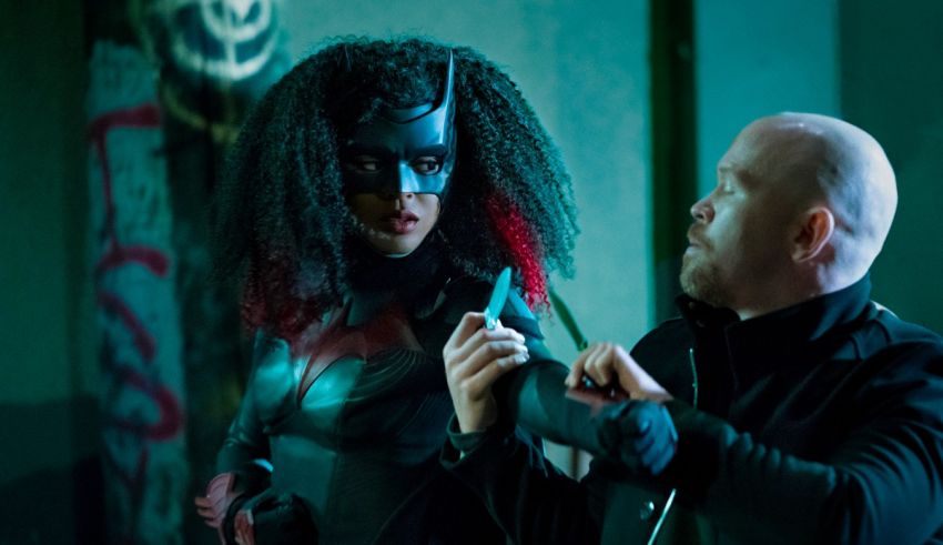 A woman in a batman costume is holding a cell phone.