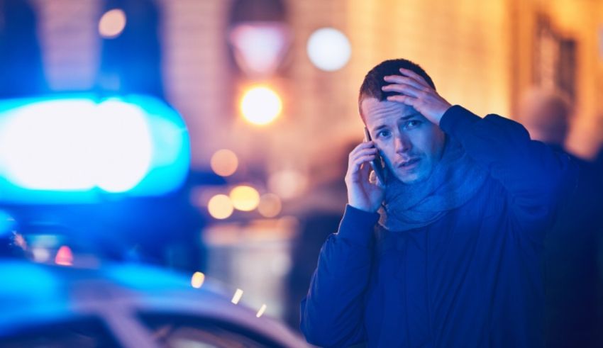 A man talking on a cell phone in front of a police car.