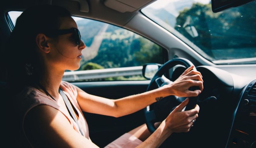 A woman driving a car with mountains in the background.