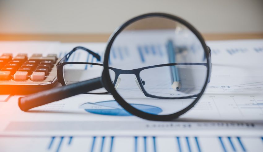 A magnifying glass and a calculator on a desk.