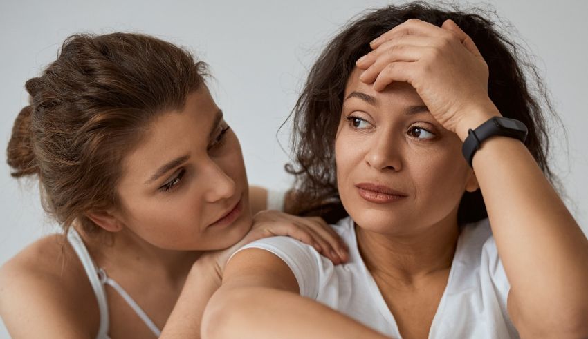 Two women looking at each other with their hands on their heads.