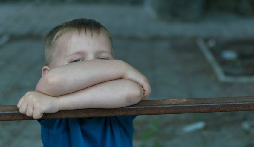 A young boy is covering his face with his hand.