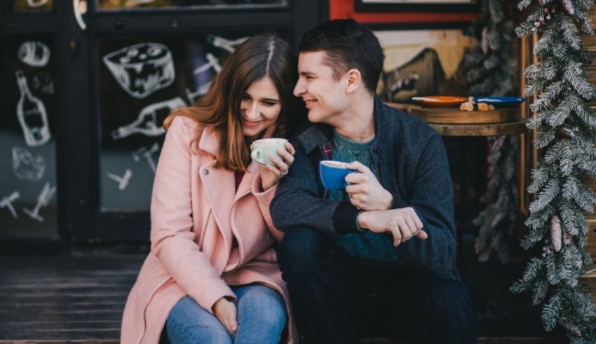 A couple sitting on the steps of a coffee shop.