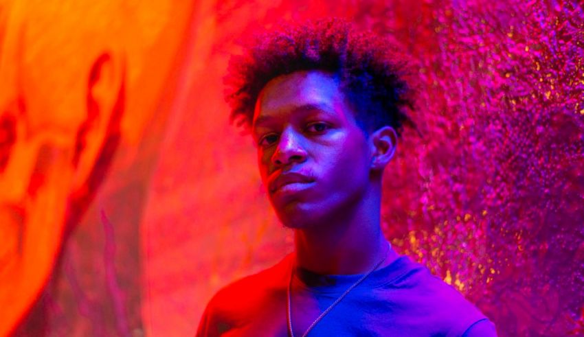 A young man standing in front of a colorful wall.