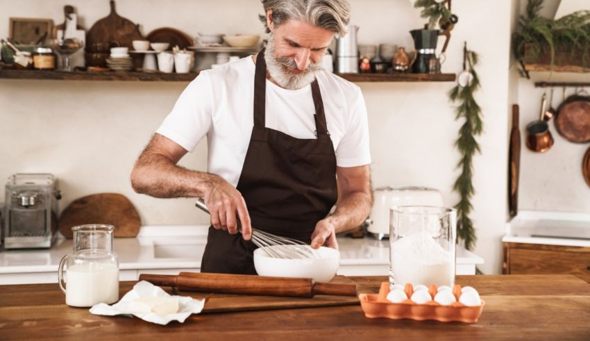 A man in an apron is mixing ingredients in a kitchen.
