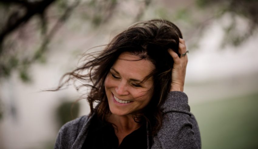 A woman smiling with her hair blowing in the wind.