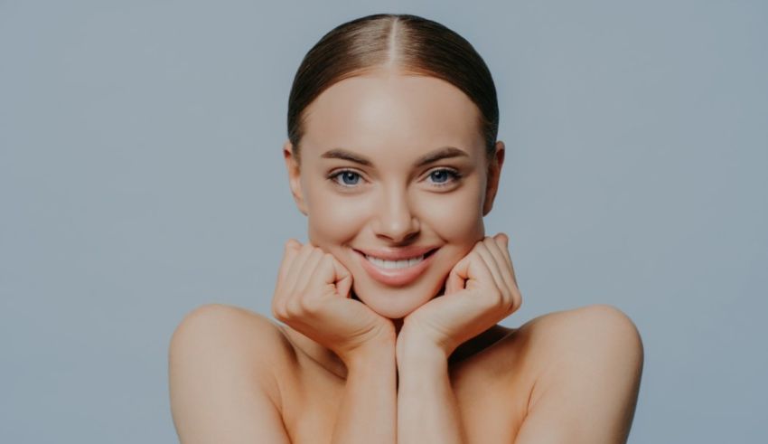 A beautiful young woman posing with her hands on her face.