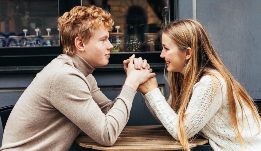 A man and woman are sitting at a table and holding hands.