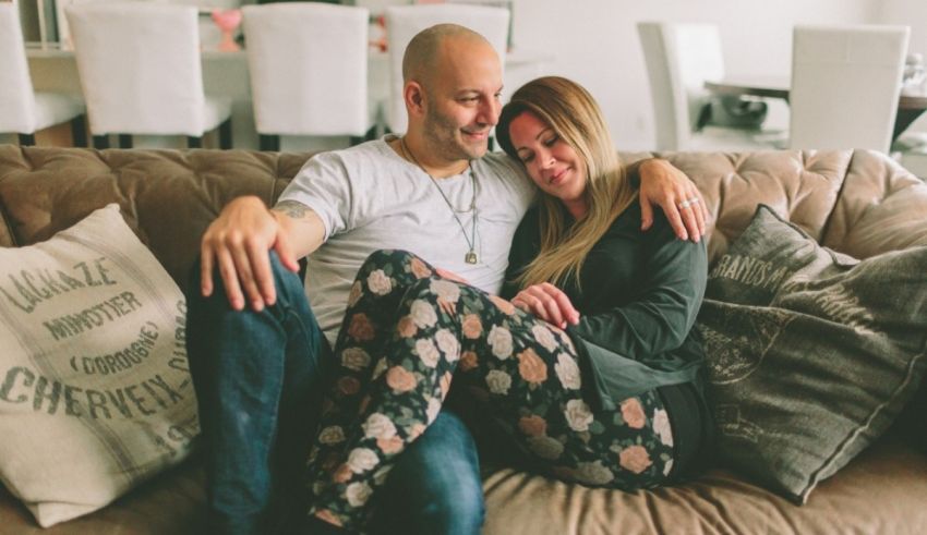 A man and woman sitting on a couch in a living room.