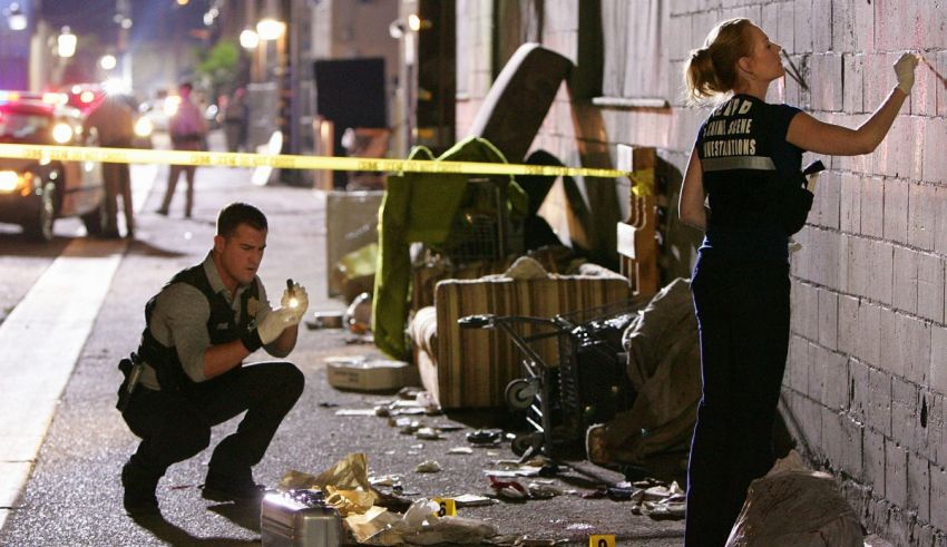 Two police officers standing next to a wall in a city.