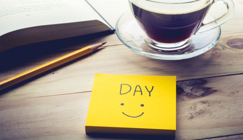 A yellow post it note with the word day next to an open book and a pencil.